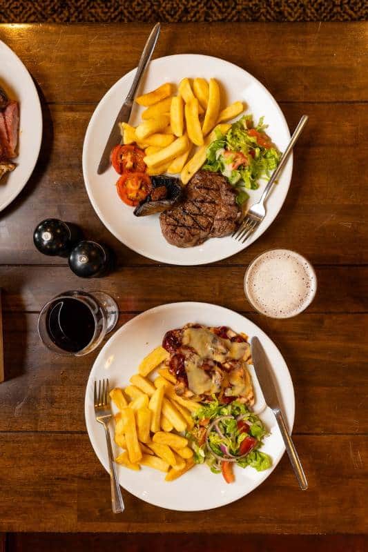 Pub food served on a table including steak and hunter's chicken main