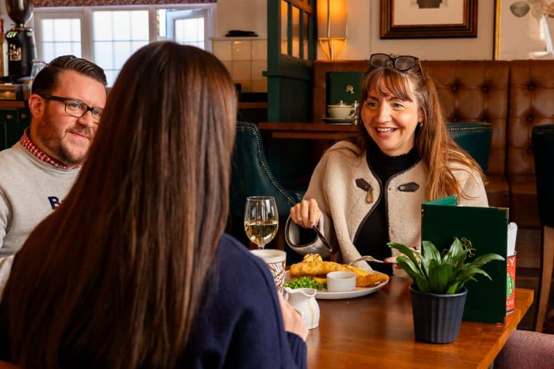 Light lunch menu: fish and chips with a family gathered around the pub table to eat.
